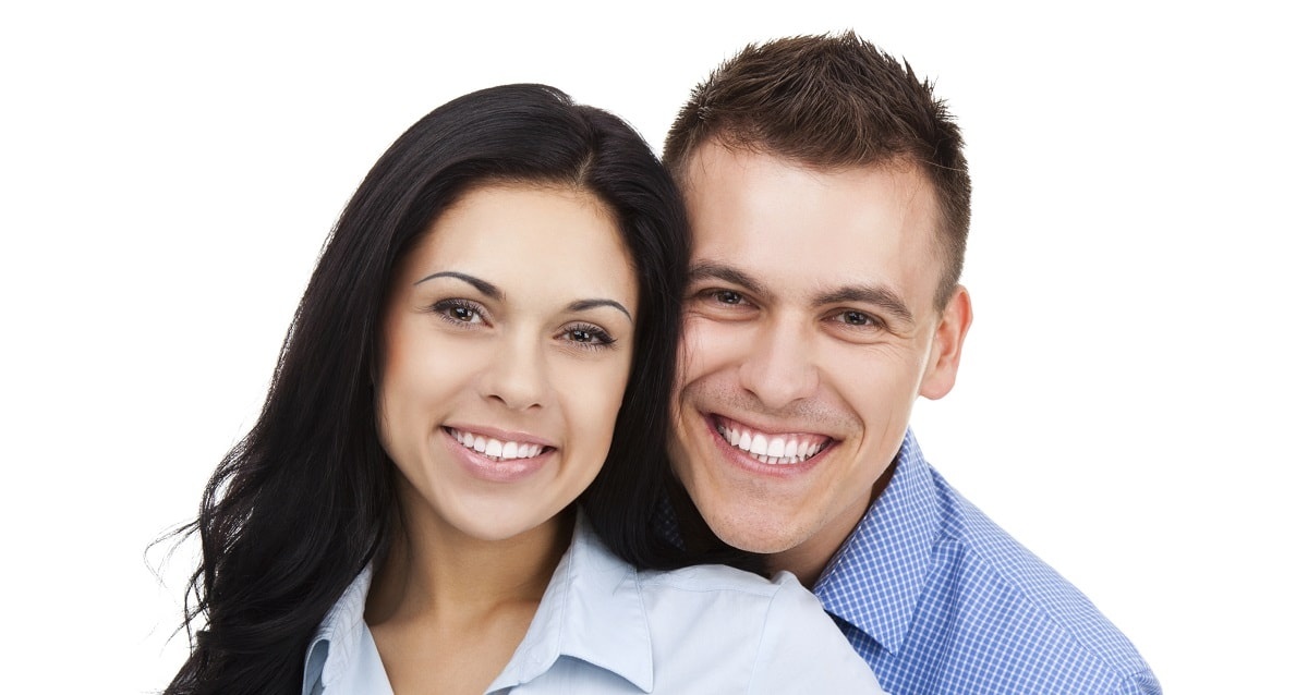 Young couple smiling into the camera.
