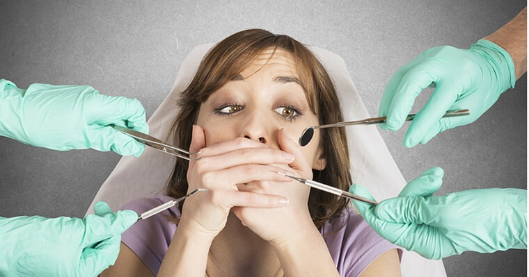 woman surrounded by dental instruments experiencing dental anxiety